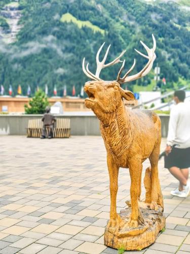 a statue of a deer with antlers is on a sidewalk at Nika Apartment - Aare Jungfrau AG in Grindelwald