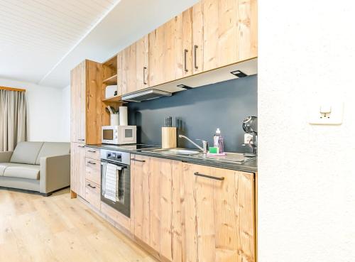 a kitchen with wooden cabinets and a couch in a room at Lauberhorn Apartment - Aare Jungfrau AG in Grindelwald