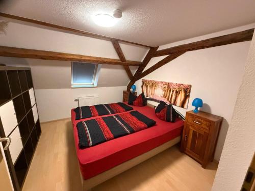 a bedroom with a red bed in a room with beams at stilvolle Dachgeschoss-Wohnung in Top-Lage in Großröhrsdorf