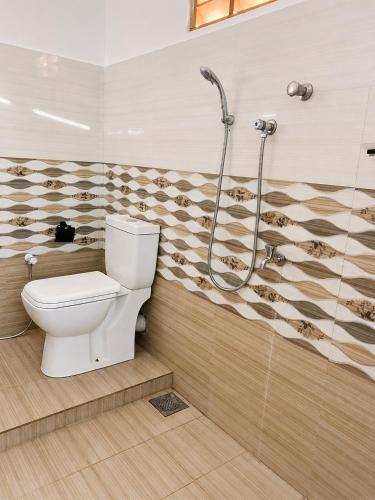 a bathroom with a toilet and a shower at French Garden Eagle Wings Inn in Trincomalee
