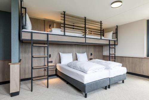 a bedroom with two bunk beds in a room at Alpine Hotel by SnowWorld in Landgraaf