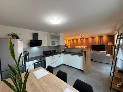 a kitchen with white cabinets and a table and a dining room at Studio Etoile Elegance in Bartenheim