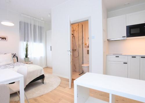 a white bedroom with a bed and a kitchen at Otepää Residence in Otepää