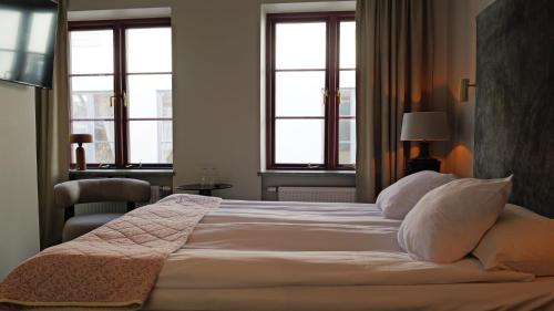 a bedroom with a large white bed with windows at Hotell Visby Börs in Visby