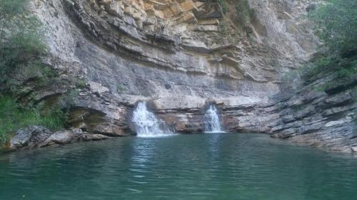 a pool of water with two waterfalls in a rocky quarry at Pinarillos in Sarvisé