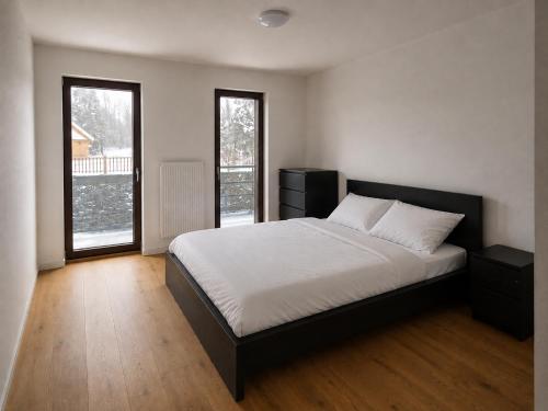 a bedroom with a large bed and two windows at Apartmán Lidická bouda in Pec pod Sněžkou