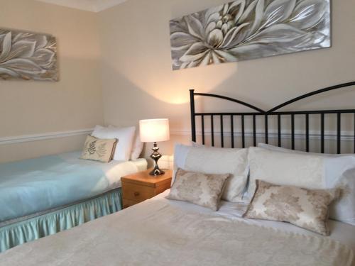 サウスエンド・オン・シーにあるCARIS Guest Houseのベッドルーム1室(ベッド2台、テーブルの上にランプ付)