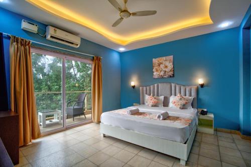 a bedroom with blue walls and a bed with a window at De Alcazar Calangute in Calangute