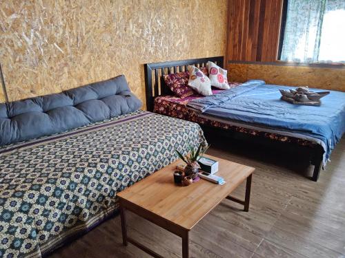 a bedroom with two beds and a wooden table at Big Hug Home in Ko Yao Noi