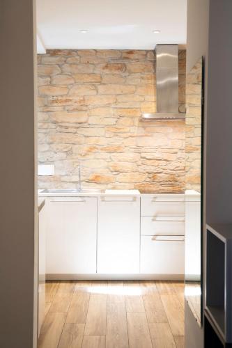 a kitchen with white cabinets and a stone wall at la Maison de Trieste Suite garage in centro 5 persone vicino Piazza Unità in Trieste