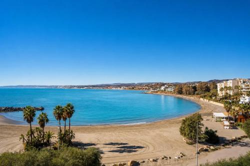 a view of a beach with palm trees and buildings at Kampaoh Estepona in Estepona