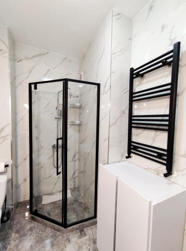 a glass shower in a bathroom with white marble walls at Ap Blessedplace Rîșcani-New Bldg in Chişinău