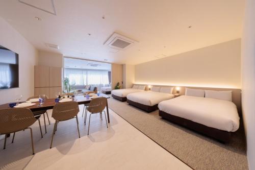 a hotel room with two beds and a table and chairs at Olympic Inn Azabu in Tokyo