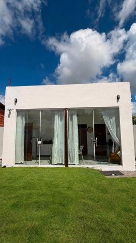 a white building with windows and a grass field at Chalé Arandu in Santo Amaro
