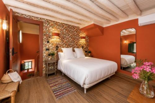 a bedroom with a large white bed and orange walls at Molino de Búlar - 1920 Olive Oil Mill Heritage in Piñar