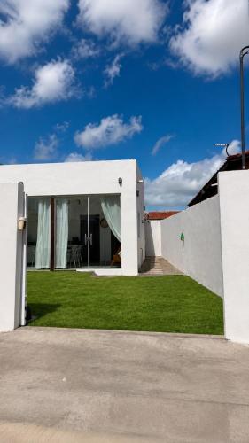 a white house with a yard with green grass at Chalé Arandu in Santo Amaro