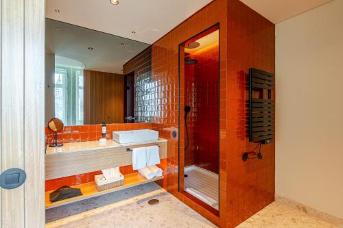 an orange tiled bathroom with a shower and a sink at NOLIA Boutique Hotel in Porto
