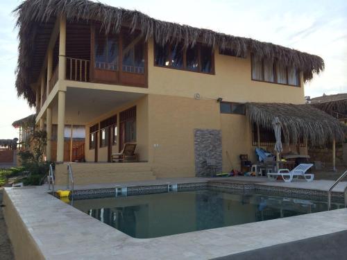 a house with a swimming pool in front of a house at Villa Sunset Beach Peru in Los Órganos