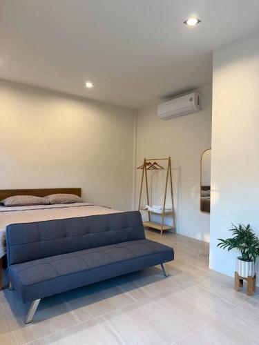 a bedroom with a bed and a blue couch at Langbaan cafe and homestay in Ban Mai