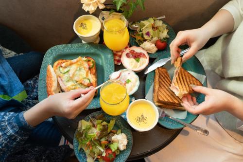 a group of people sitting at a table with food at 7 Rooms Hotel & Cafe - ディズニーと空港までバス1本 - 全室キッチン付き in Tokyo