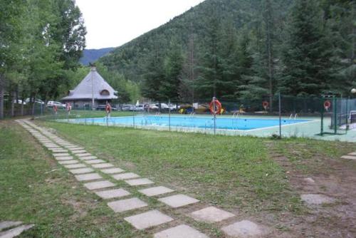 a swimming pool in a park with people in it at El Chate Tiendas in Sarvisé