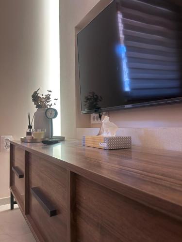 a wooden dresser with a large television on a wall at Apartman Aleksandra 2 in Bečej