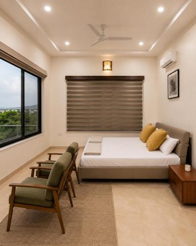 a bedroom with a bed and two chairs and a window at Kanchan Jayanti Villa in Khandāla