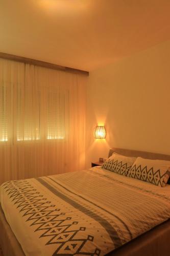 a bedroom with a bed and a window with a lamp at Apartment in Shtip in Štip
