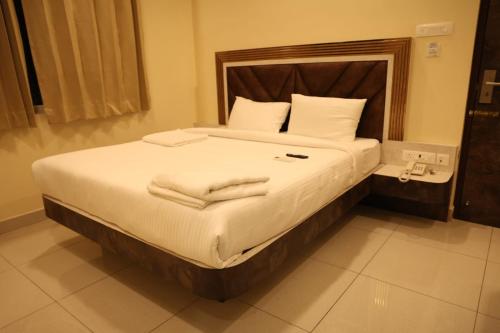 a bedroom with a large bed with white sheets and pillows at Kings Residency in Chennai