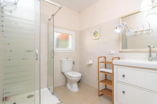 a bathroom with a toilet and a glass shower at Sol I Vent in Cala Santanyi