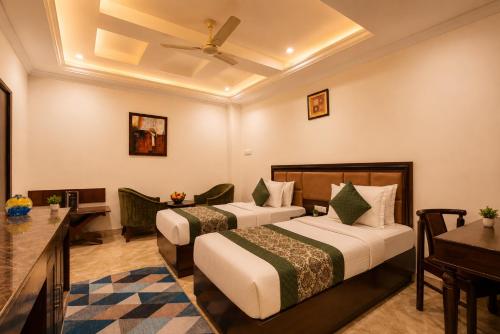 a hotel room with two beds and a desk at Airport La Sapphire Hotel & Restaurant in New Delhi