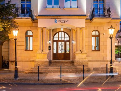 a yellow building with a door and stairs in front at Rezydent Hotel Sopot - MGallery Collection in Sopot