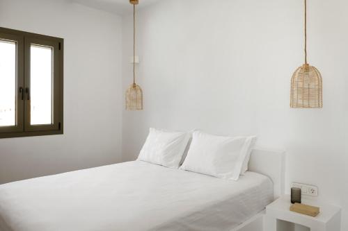 a white bed with white pillows and a window at Halo Tinos - PHOEBUS in Tinos