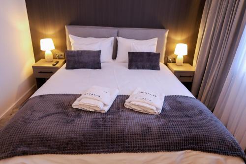 a bedroom with a large bed with two towels on it at Nivalis Resort and SPA in Muntele Băişorii