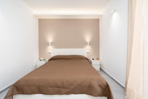 a white bedroom with a bed and two night stands at GiuMar Apartments Acitrezza in Aci Catena