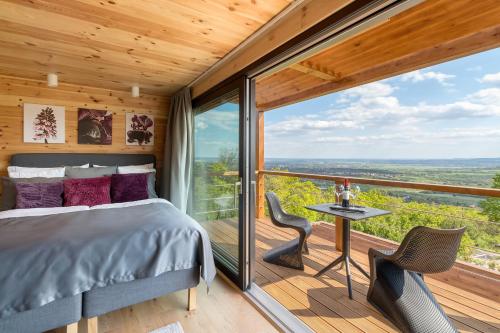 a bedroom with a bed and a balcony with a view at Szarvashegy Panoráma Apartman in Szentendre