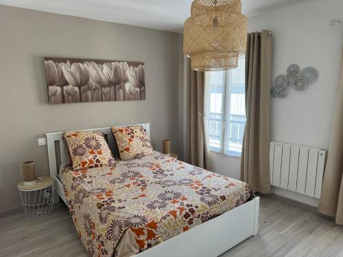 a bedroom with a bed with a comforter and a window at Le Marais Vous - Duplex en centre-ville. in Provins