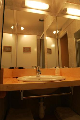 a bathroom with a sink and a large mirror at Hôtel Bar Restaurant de la Poste Le 1900 in Jougne