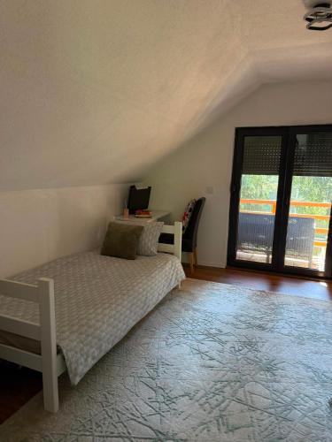a bedroom with a bed and a desk and a window at Hidden pines in Gornji Čevljanovići