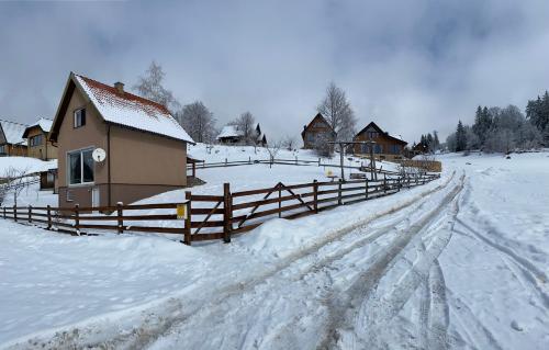 a snow covered field with a house and a fence at BiSER PANČIĆA in Sekulić 