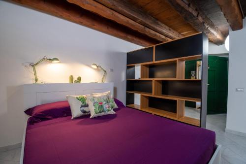 a bedroom with a purple bed and shelves at Sotto la torre Apartment in Cagliari