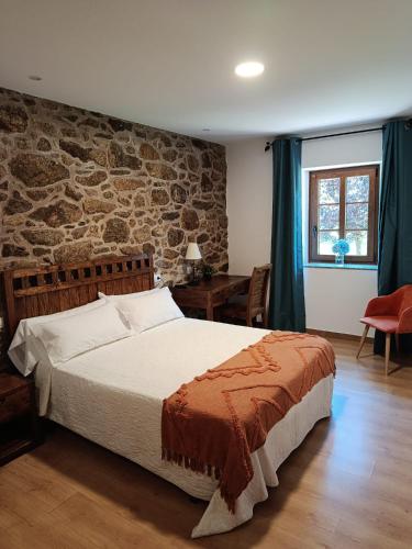 a bedroom with a bed and a stone wall at Casa Ceferinos in Muxia