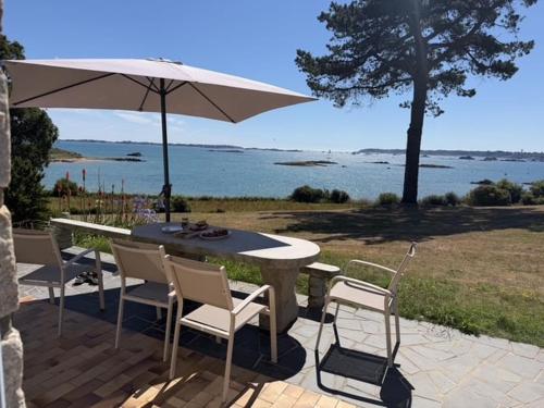 a table and chairs with an umbrella on a patio at La Bretonne vue mer in Lanmodez