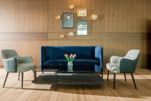a blue couch with two chairs and a vase of flowers at Radisson Blu Hotel Amsterdam Airport, Schiphol in Schiphol