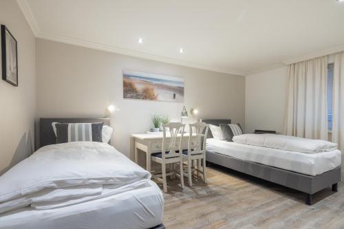 two beds in a room with a table and a desk at Düne in Keitum