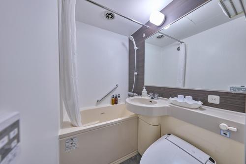 a bathroom with a sink and a toilet and a mirror at Smile Hotel Tokyo Nihonbashi in Tokyo