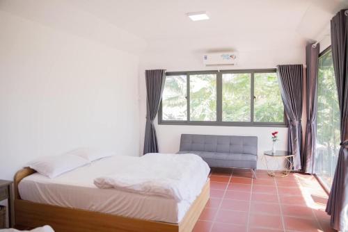 a bedroom with a bed and a couch and a window at LUA Farmstay in Bà Rịa