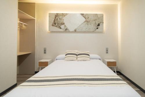 a bedroom with a white bed with two pillows on it at Apartamentos El Real in Mota del Cuervo
