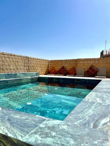 a swimming pool with blue water and some chairs at Riad Nirvana in Marrakesh