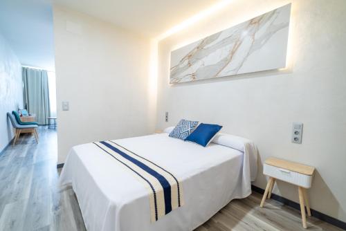 a bedroom with a large white bed with a painting on the wall at Apartamentos El Real in Mota del Cuervo